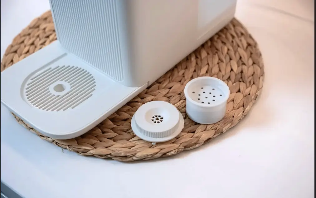 Filtr remineralizujący Klarta Aqva na podkładce na blacie.